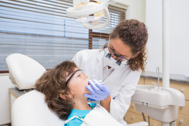 pediatric dentist examining little boys teeth dentists chair