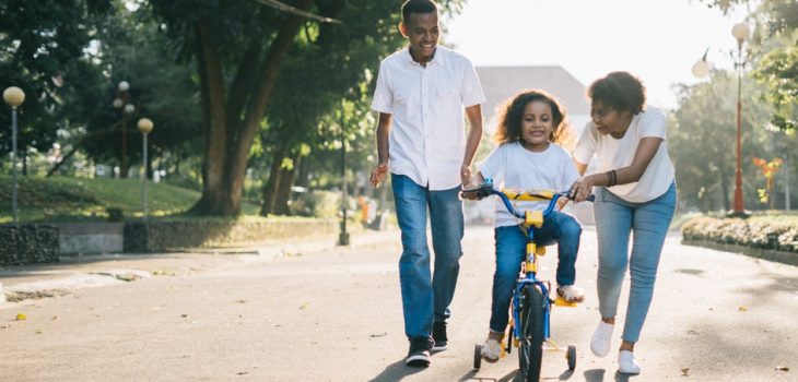 man-standing-beside-his-wife-teaching-their-child-how-to-1128318